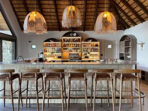 a bar with wooden stools in a room at Simbavati Waterside in Klaserie Private Nature Reserve