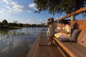 two women sitting on a dock reading a book at Simbavati Waterside in Klaserie Private Nature Reserve