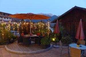 a patio with a table and an umbrella and lights at Hotel Garni Zerzer in Serfaus