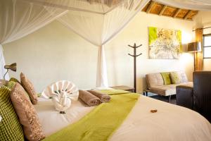 a bedroom with a large white bed with a room with a cross at Umkumbe Safari Lodge Riverside in Skukuza