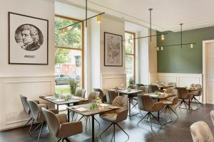 una sala da pranzo con tavoli, sedie e finestre di HYPERION Hotel Salzburg a Salisburgo