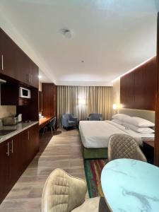 a hotel room with two beds and a table and chairs at City Seasons Suites in Dubai