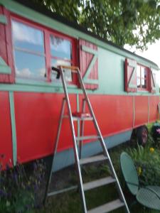 a ladder on the side of a red and white train at La Roulotte De Lola - Chambre d'hôtes in La Celle