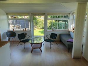 a living room with a couch and chairs and windows at Slotsgaardens hus in Jels