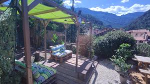 une terrasse en bois avec un parasol vert et un banc dans l'établissement Vernet Jardin, à Vernet-les-Bains