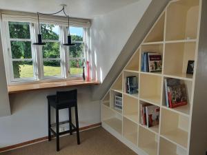 ein Treppenhaus mit Bücherregalen und einem Hocker neben einem Fenster in der Unterkunft Slotsgaardens hus in Jels