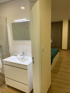 baño con lavabo, espejo y cama en Quinta da Menina Guest House, en Vila Real
