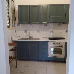 a kitchen with green cabinets and a sink and a stove at La casetta con cortile in Lecce