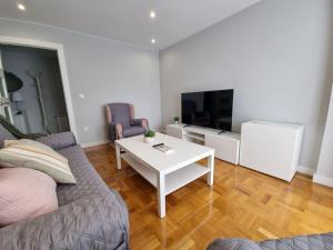 een woonkamer met een bank, een tafel en een tv bij 153A 3 dormitorios Barrio de La Arena con parking in Gijón