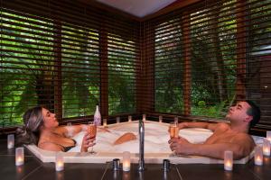 Ein Mann und eine Frau in einer Badewanne mit Kerzen in der Unterkunft Linden Gardens Rainforest Retreat in Mount Dandenong