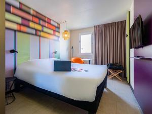 een hotelkamer met een groot bed met een laptop erop bij ibis Styles Perpignan Centre Gare in Perpignan