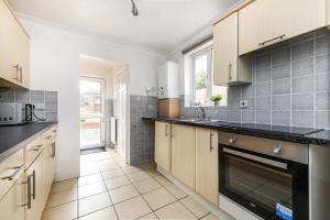 Una cocina con gabinetes blancos y encimeras negras. en The White Rose Crown, Free Parking & Wifi, 10beds, en Colchester