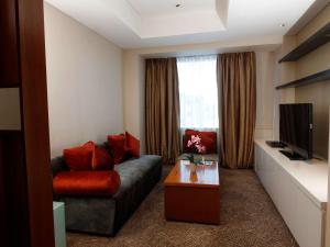 a living room with a couch and a tv at Novotel Balikpapan in Balikpapan