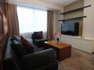 a living room with a couch and a flat screen tv at Novotel Balikpapan in Balikpapan