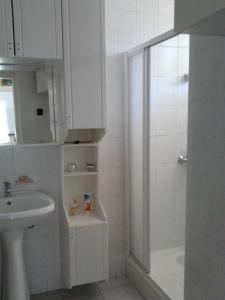 a white bathroom with a shower and a sink at Balatonberényi Vendégház in Balatonberény