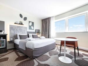 a bedroom with a large bed and a table at Mercure Compiègne Sud in Compiègne