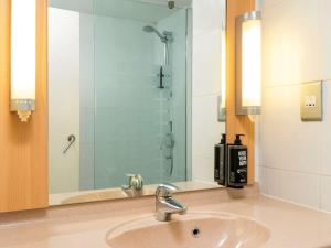 a bathroom with a sink and a shower with a mirror at ibis York Centre in York