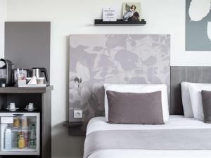 a bedroom with a bed with a flower patterned wall at Mercure Compiègne Sud in Compiègne