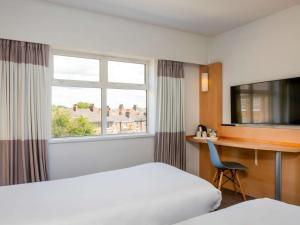 a hotel room with a bed and a desk and a window at ibis York Centre in York