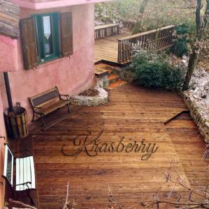 a wooden deck with a bench on a house at Krasberry Ježev brlog in Komen