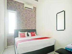 um quarto com uma cama com almofadas cor-de-rosa em OYO 90492 Papi Inn Guesthouse em Palangkaraya