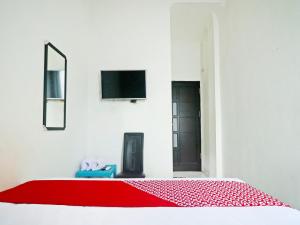 um quarto com uma cama vermelha e uma televisão na parede em OYO 90492 Papi Inn Guesthouse em Palangkaraya