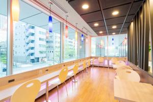 a waiting room with chairs and tables and windows at Rose Stay Tokyo Shiba Park in Tokyo