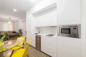 cocina con armarios blancos y sillas amarillas en una habitación en Room Boutique Calma Laura By KubiK, en Cáceres