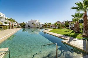 een zwembad in een resort met palmbomen en huizen bij CDG- Cortijos Del Golf by Roomservices in Estepona