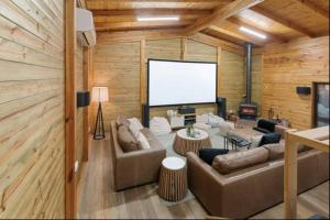 a living room with a couch and a large screen at AALFOR LODGE - Luxury Cabin with Spa & Cinema! in Mount Buller