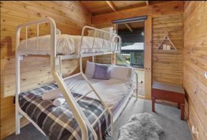 a bedroom with two bunk beds in a log cabin at AALFOR LODGE - Luxury Cabin with Spa & Cinema! in Mount Buller