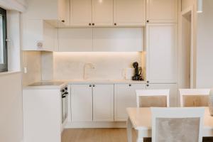 cocina blanca con armarios blancos y mesa en Carmen Residence Apartments, en Opatija
