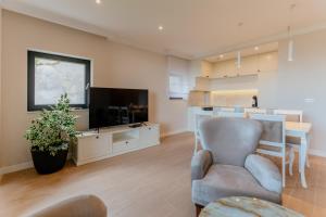 sala de estar con TV, sofá y silla en Carmen Residence Apartments, en Opatija
