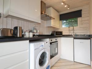 a kitchen with white cabinets and a washer and dryer at Lanteglos 18 in Camelford