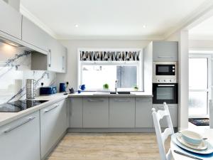 a kitchen with white cabinets and a table and a window at Pass the Keys Newly refurbished modern bungalow - Pets Welcome in Swansea