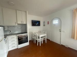 a kitchen with white cabinets and a table with chairs at Ca Mestral Son Bou Urbanización típica menorquina. in Son Bou