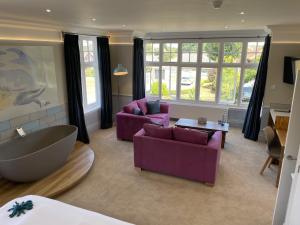 a living room with purple furniture and a large tub at The Randolph Hotel in Southwold