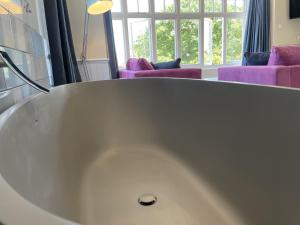 a white bath tub in a room with purple furniture at The Randolph Hotel in Southwold