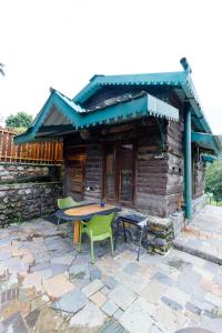 a patio with a table and chairs in front of a cabin at Seegreen Lodges in Mussoorie