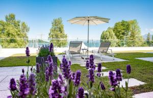 un jardín con flores púrpuras y una sombrilla en Yachthotel Chiemsee GmbH, en Prien am Chiemsee
