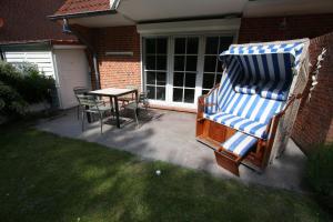 a patio with a table and chairs and a beach chair at Ferienwohnung "Zum Böhler Leuchtturm" in Sankt Peter-Ording