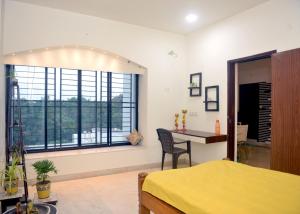 a bedroom with a bed and a desk and windows at Paradise Homestay Civil Lines in Nagpur