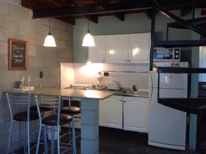 a kitchen with white cabinets and a counter with stools at Loft Hadas del Bosque in Mar de las Pampas