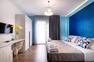 a bedroom with blue walls and a bed and a desk at Zaffiro Lavico rooms Etna nature sea in Acireale