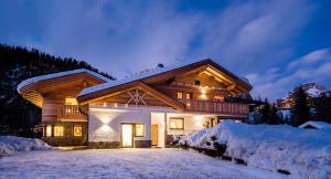 a log home in the snow at night at Apartments Piciulei in Selva di Val Gardena