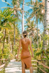 a woman in an orange dress walking down a path at La Cocoteraie Ecolodge - Luxury Glamping Tents in Gili Trawangan