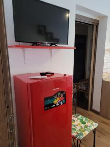 einen roten Kühlschrank mit einem TV darüber. in der Unterkunft La dimora di Enrico in Catania