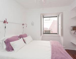 een witte slaapkamer met een bed met paarse en witte kussens bij Shabby Chic Bairro Alto in Lissabon