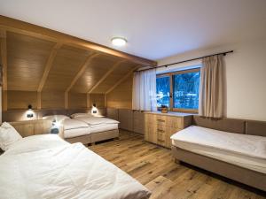 a bedroom with three beds and a window at Apartments Piciulei in Selva di Val Gardena