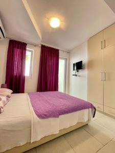 a bedroom with a large bed with purple sheets at Apartmani Bonik in Budva
